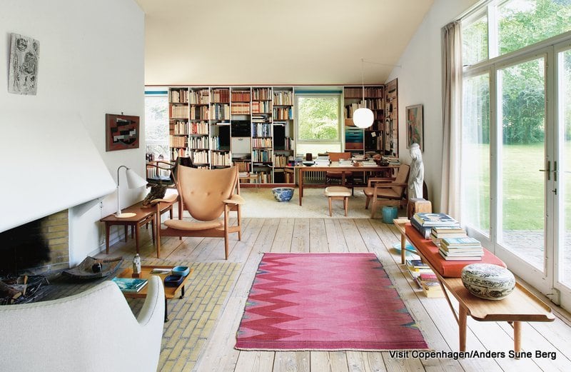 Finn Juhl’s own house is a textbook example of his project as an architect and as a furniture designer. The house at Kratvænget 15 in Charlottenlund, north of Copenhagen was built in 1942. It is situated in rural surroundings on a 1700 m² site adjoining the park at Ordrupgaard. 

The house is composed of two blocks standing at right-angles to each other. In one block is a large living room and a small study, while the second block houses the kitchen, dining room, bedrooms and bathroom. The two blocks are joined by an entrance hall which opens to the garden. The house is an early example of open-plan, with a characteristic view through its rooms. Although each room has its own clear function, it is always possible to look from one room to the next as you walk through the house and there is always a view of the garden. The ceilings are painted in pale light yellow and when they reflect the light from outside, they resemble the roof of a tent with light shining through. The house is brick-built and the façade is plastered in a grey-white shade which offers it a soft, matt effect. Therefore the house appears light against the contrasting dark woodland backdrop.